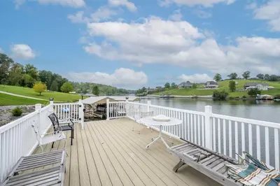 a wooden deck with two chairs and a table on the water at Lazy Days Waterfront for 12 in Williamstown