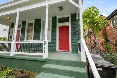 a green house with a red door and stairs at Stylish Modern Gem in the HIlls in Cincinnati