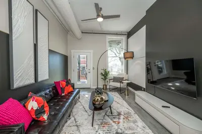 a living room with a black leather couch and a tv at Queen City Views Suites in Cincinnati