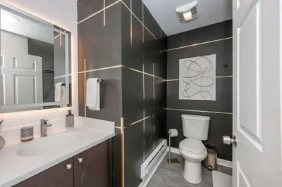 a bathroom with a sink and a toilet and a mirror at Queen City Views Suites in Cincinnati