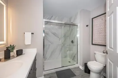 a white bathroom with a shower and a toilet at Queen City Views Suites in Cincinnati