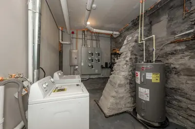 a laundry room with a washer and a stone wall at Queen City Views 1 Chic 1 BDR in Cincinnati