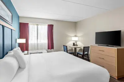 a hotel room with a bed and a flat screen tv at Suburban Studios Charleston - Civic Center in Charleston