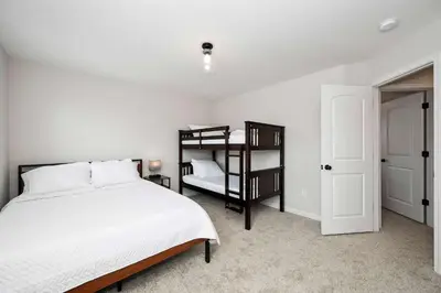 a white bedroom with a bed and a book shelf at Lunar Haven - Gorgeous 5 BDR in Walton