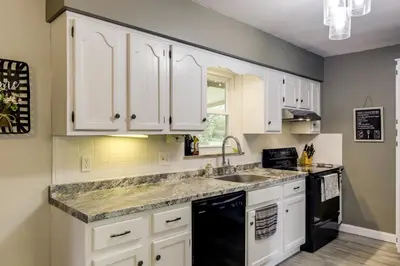 a kitchen with white cabinets and a sink at 10 Mi to Dtwn Cincinnati Home with Patio and Yard! in Cincinnati