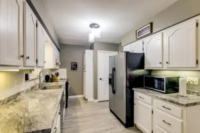 a kitchen with white cabinets and a stainless steel refrigerator at 10 Mi to Dtwn Cincinnati Home with Patio and Yard! in Cincinnati
