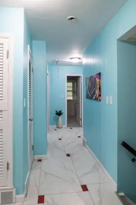 a hallway with blue walls and a tile floor at Little Paris- In Affluent University HTS in University Heights