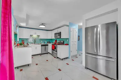 a kitchen with white cabinets and a refrigerator at Little Paris- In Affluent University HTS in University Heights