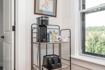 a coffee maker on a stand next to a window at Historic Ludlow Apt B in Ludlow