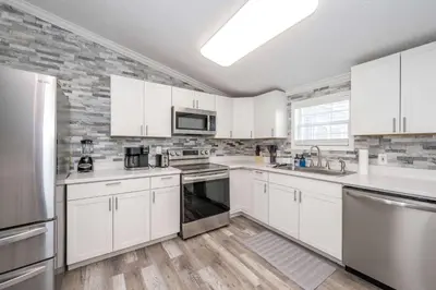 a large white kitchen with white cabinets and appliances at Stillwater Hollow - For 10! in Williamstown