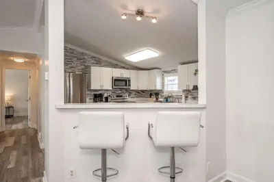 a kitchen with white cabinets and two white chairs at Stillwater Hollow - For 10! in Williamstown