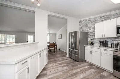 a kitchen with white cabinets and a stainless steel refrigerator at Stillwater Hollow - For 10! in Williamstown