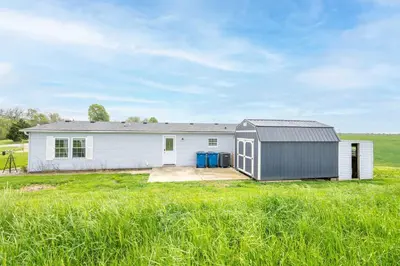 a white house with a garage in a field at Stillwater Hollow - For 10! in Williamstown