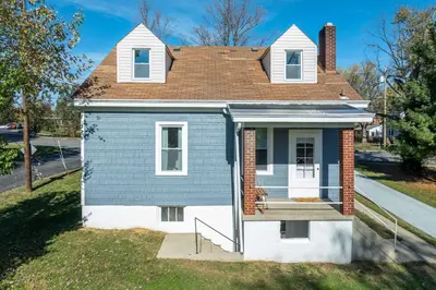 a small blue house with a porch on a street at Bridgetown Bungalow in Cincinnati