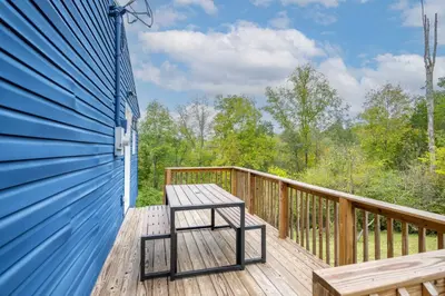 a wooden deck with a bench on the side of a blue building at The Ark Encounter Getaway in Williamstown