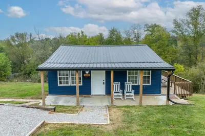 a blue tiny house with two chairs in a yard at The Ark Encounter Getaway in Williamstown