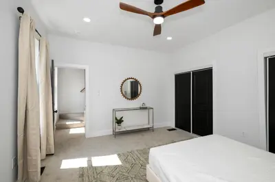 a white bedroom with a ceiling fan and a mirror at Heights on Wayne by Blackhouse in Cincinnati
