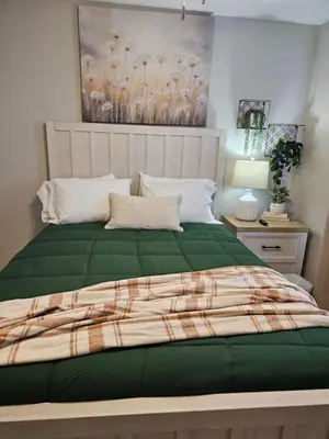 a bedroom with a large bed with a green comforter at New Construction 4 Bedroom Ranch in Trenton in Trenton