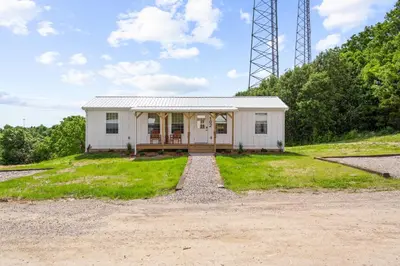 a white house on a hill with a gravel driveway at 5 Neighboring Cabins at Eden Reserve - Front Five in Williamstown