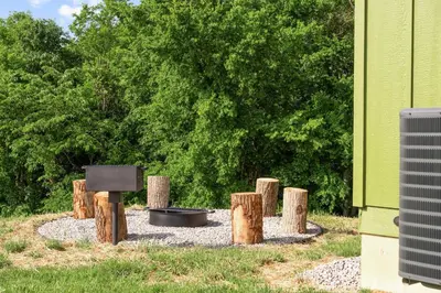 a fire pit with logs and a pan in a yard at The Lodges at Eden Reserve - Cabin Loop - Near Ark in Williamstown
