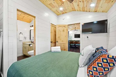 a bedroom with a green bed and a bathroom at The Lodges at Eden Reserve - Cabin Loop - Near Ark in Williamstown