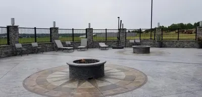 a fire pit in a patio with chairs and a fence at Garland Hotel in New Concord