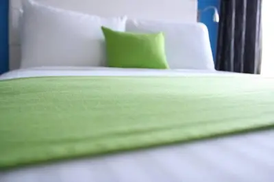 a bed with green sheets and a green pillow at Garland Hotel in New Concord