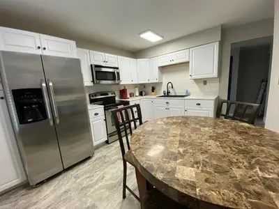 a kitchen with a table and a stainless steel refrigerator at London Maisonette - Red Door in London