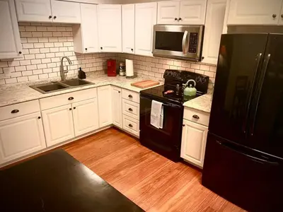 a kitchen with white cabinets and a black refrigerator at London Maisonette - Black Door in London