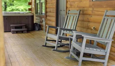 two rocking chairs and a table on a porch at Trails End Cabin- Sauna, Arcade, Hot Tub, Firepit in Logan