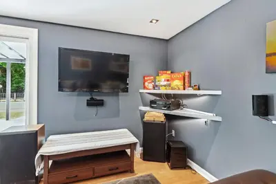 a living room with a flat screen tv on a blue wall at Spacious Family Getaway- Salt Water Pool & Hot Tub in Lyndhurst