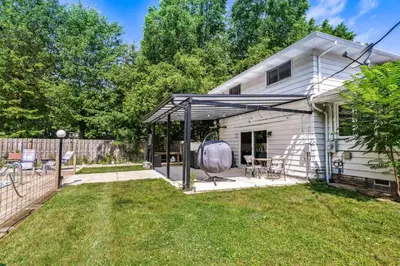 a backyard of a white house with a patio at Spacious Family Getaway- Salt Water Pool & Hot Tub in Lyndhurst
