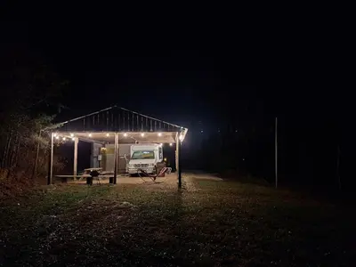 a truck parked under a tent at night at Covered Bridge Tiny Home Bus On The Water In Rrg in Stanton
