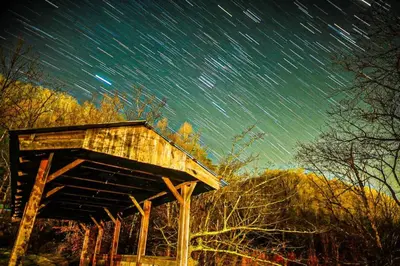 a wooden shelter with star trails in the sky at Covered Bridge Tiny Home Bus On The Water In Rrg in Stanton