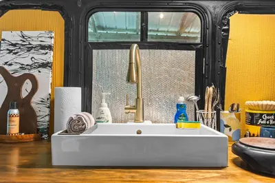 a bathroom with a white sink and a window at Covered Bridge Tiny Home Bus On The Water In Rrg in Stanton