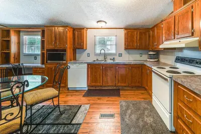 a kitchen with wooden cabinets and white appliances at Well and Cellar Near Kanawha River and ATV Trails!