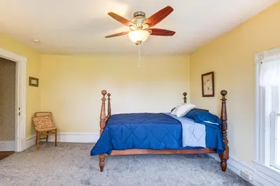 a bedroom with a bed with a ceiling fan at 2 Mi to Chardon Square Spacious Farmhouse in Concord