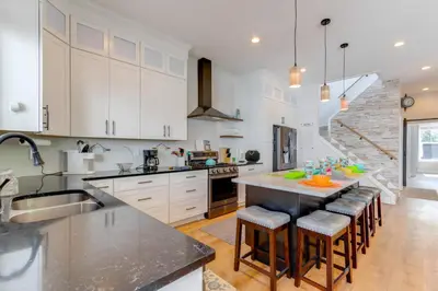a kitchen with white cabinets and a island with bar stools at Steps to Buckeye Lake Family-Friendly Home in Buckeye Lake