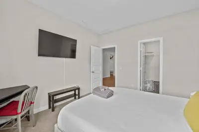 a white bedroom with a bed and a desk and a television at Modern, newer home, King bed, near Indianapolis in Pendleton