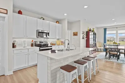 a kitchen with white cabinets and a kitchen island with bar stools at Modern, newer home, King bed, near Indianapolis in Pendleton