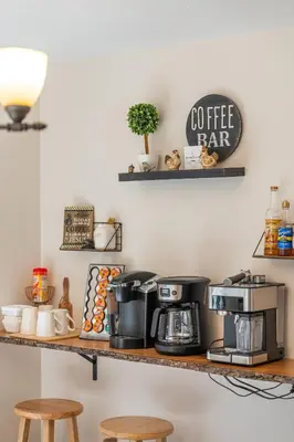 a shelf with coffee machines on it with two stools at Spring Mountain Cove in Warsaw