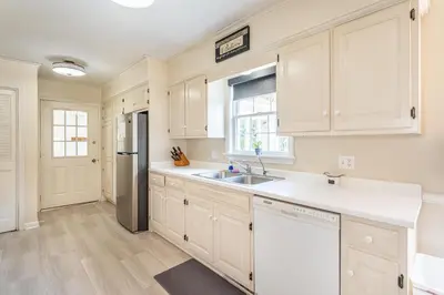 a kitchen with white cabinets and a stainless steel refrigerator at Country Cottage in Apple Creek