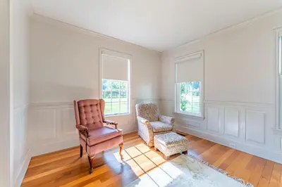 an empty living room with a chair at Country Cottage in Apple Creek