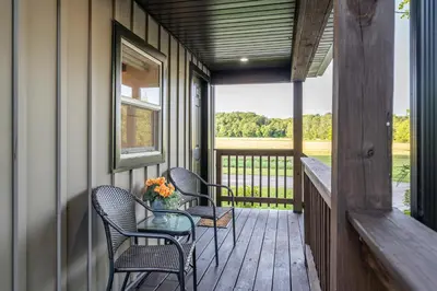 a porch with two chairs and a table with flowers on it at White Oak Cottage in Mount Orab
