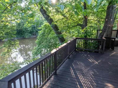 a wooden deck next to a river with trees at White Oak Cottage in Mount Orab