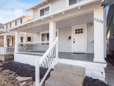 a white house with a porch with a white door at Oakwood Charm Family-Friendly 3BR Getaway in Columbus