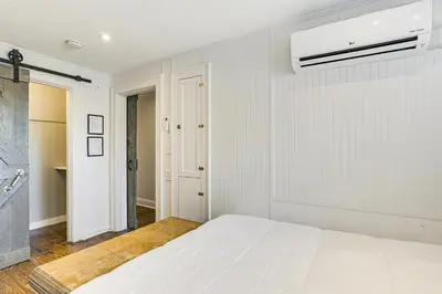 a white bedroom with a bed and a air conditioner at 2 Mi to Ark Encounter Condo on Main Street! in Williamstown