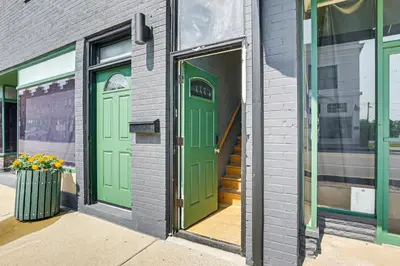 a building with two green doors and a window at 2 Mi to Ark Encounter Condo on Main Street! in Williamstown