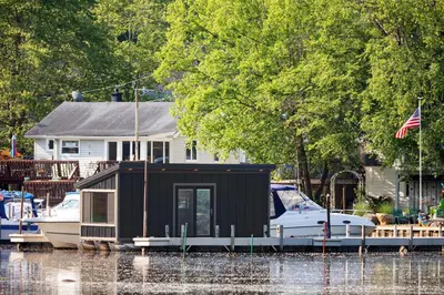 a small house on a boat in the water at Floating Tiny Home #1 in Vermilion