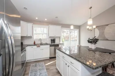 a kitchen with white cabinets and a stainless steel refrigerator at Ark Adventure Retreat in Walton